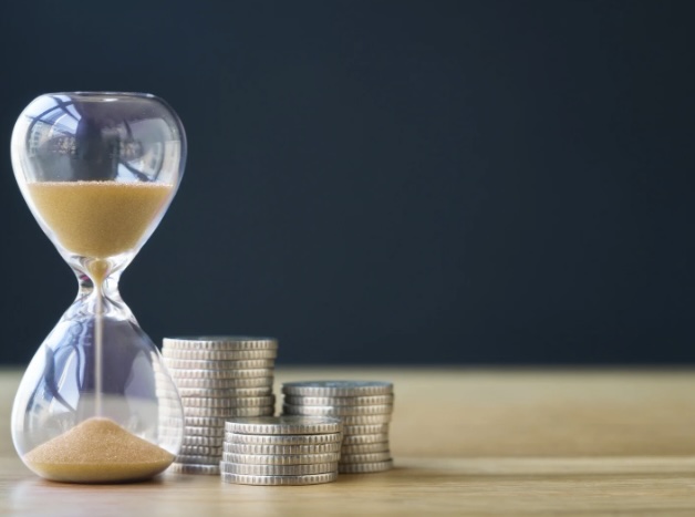 Stacked coins next to an hourglass